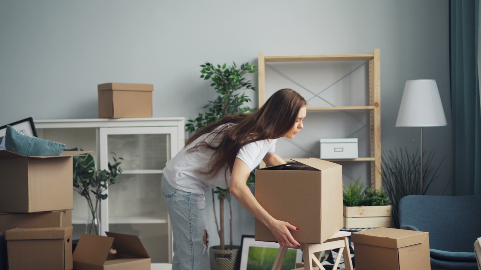 a woman moving boxes in a living room, renters